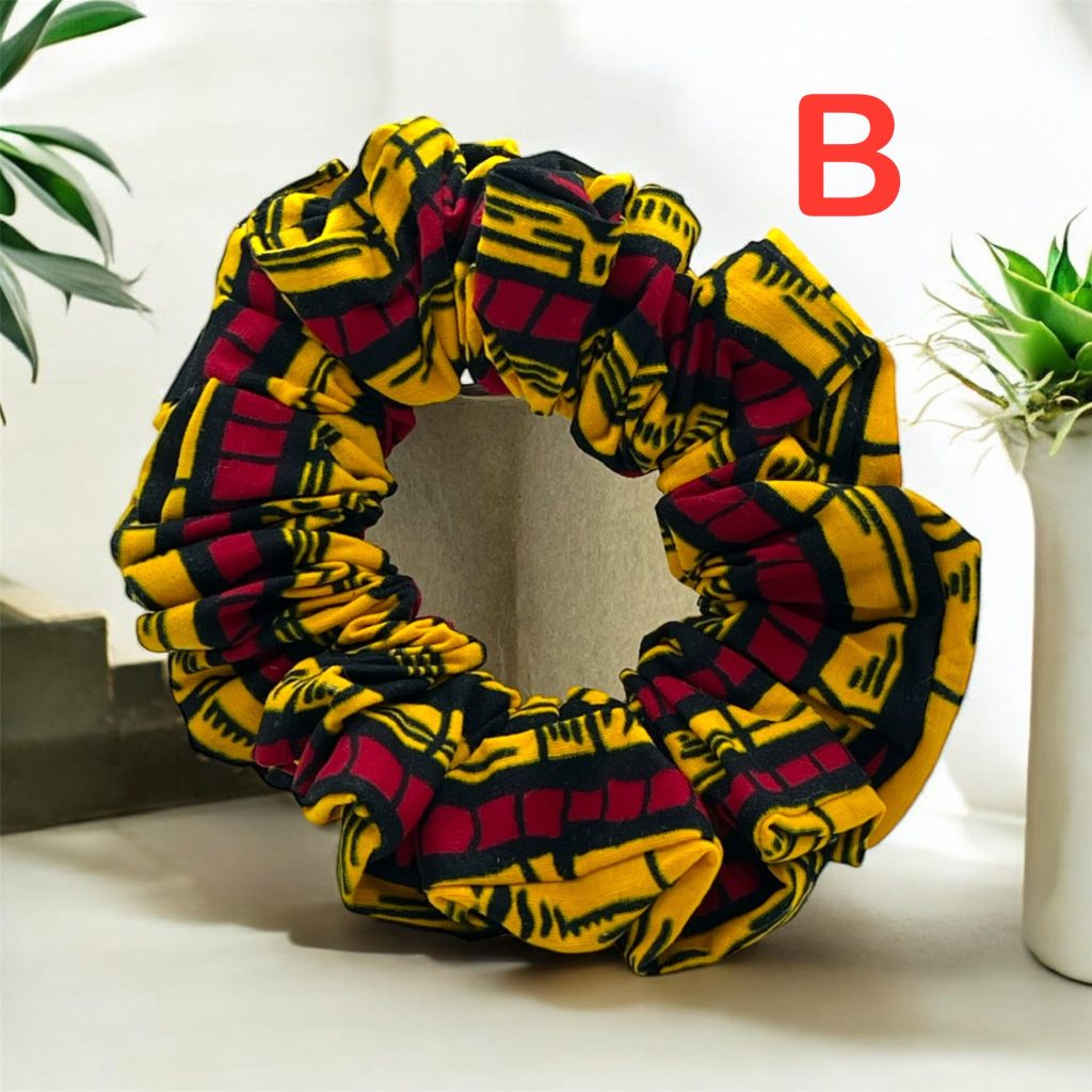 Yellow, red, and black patterned scrunchies for the hair placed on a table with plants in the background.