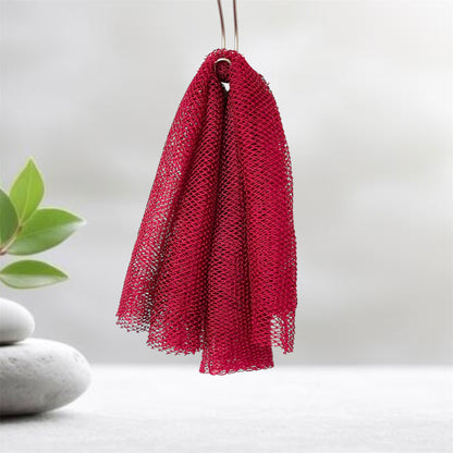 Maroon mesh scrubber hanging on a hook with a plant and stones in the background