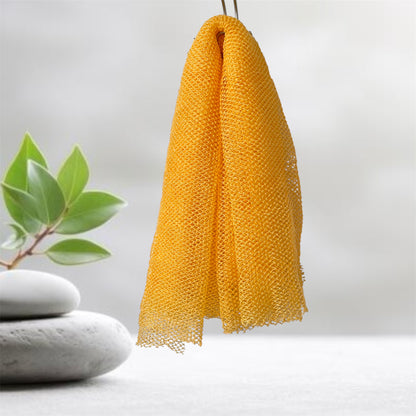 Golden yellow mesh scrubber hanging on a hook with a plant and stones in the background