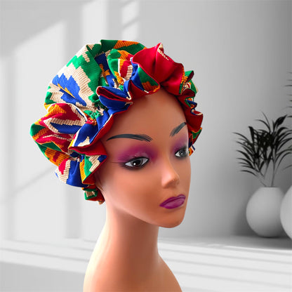 "A mannequin head wearing a stylish hair bonnet with a bold geometric pattern, featuring colors green, blue, red, yellow, white, and orange, set against a blurred indoor background with potted plants."