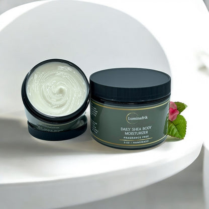 Luminafrik Daily Shea Body Moisturizer jar with open lid on a white surface